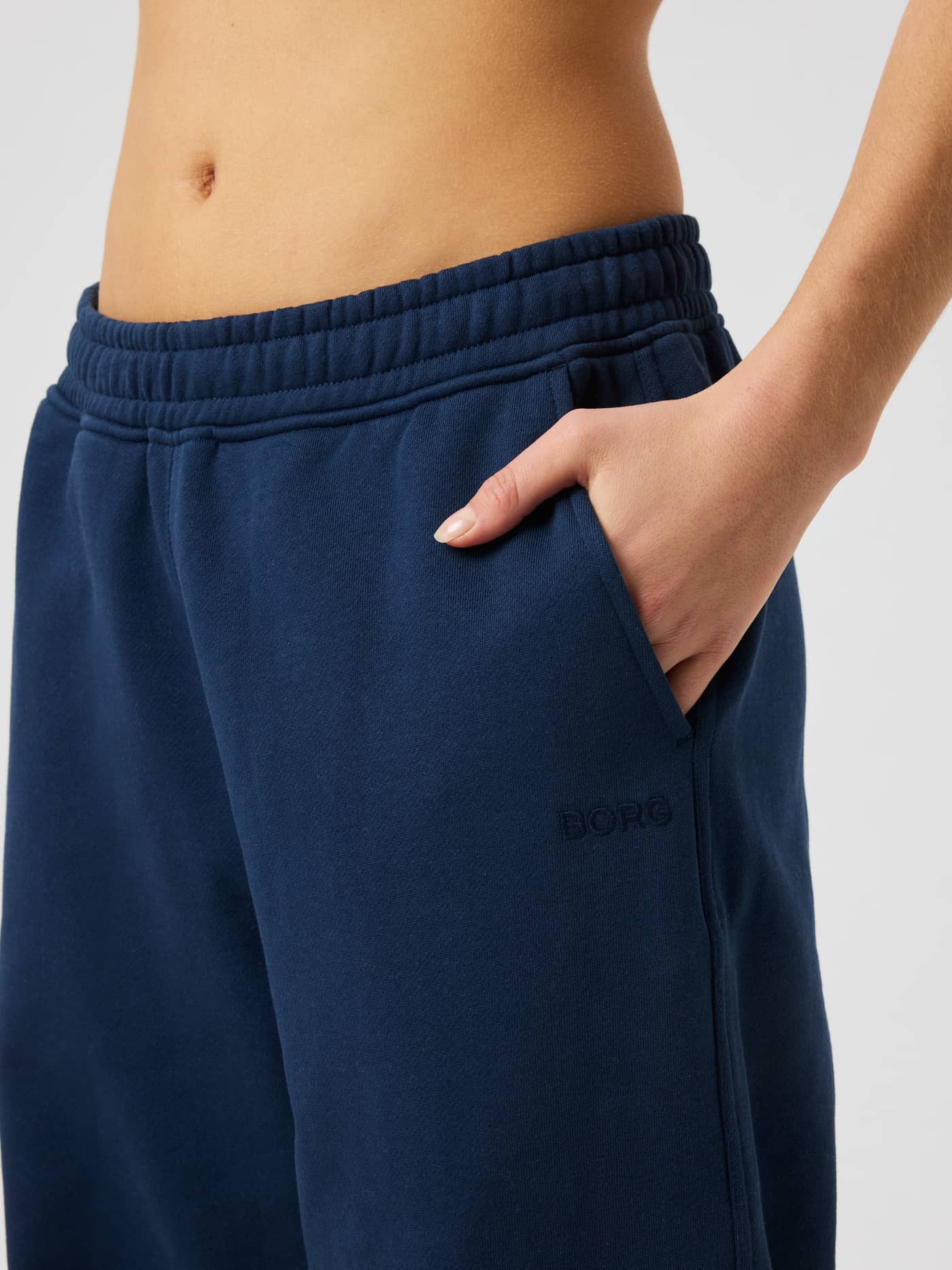 Närbild av Studio Oversized Straight Sweatpants i Dress Blues (marinblå) med fokus på midjan och sidofickan. - Image 4
