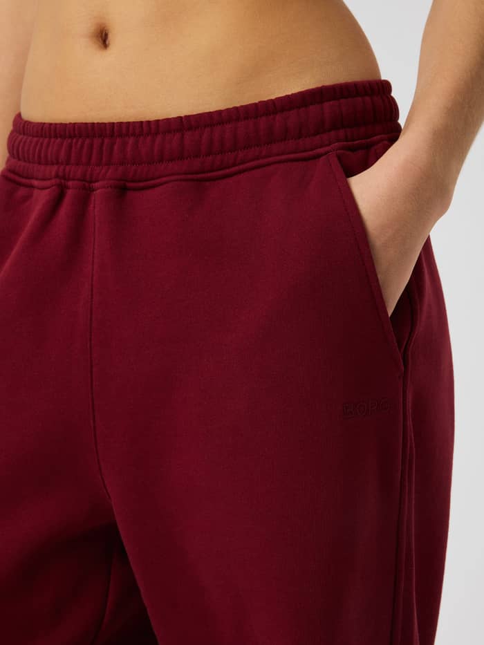 Close-up of the Studio Oversized Straight Sweatpants in Cabernet (Red) highlighting the elastic waistband and pocket detail.