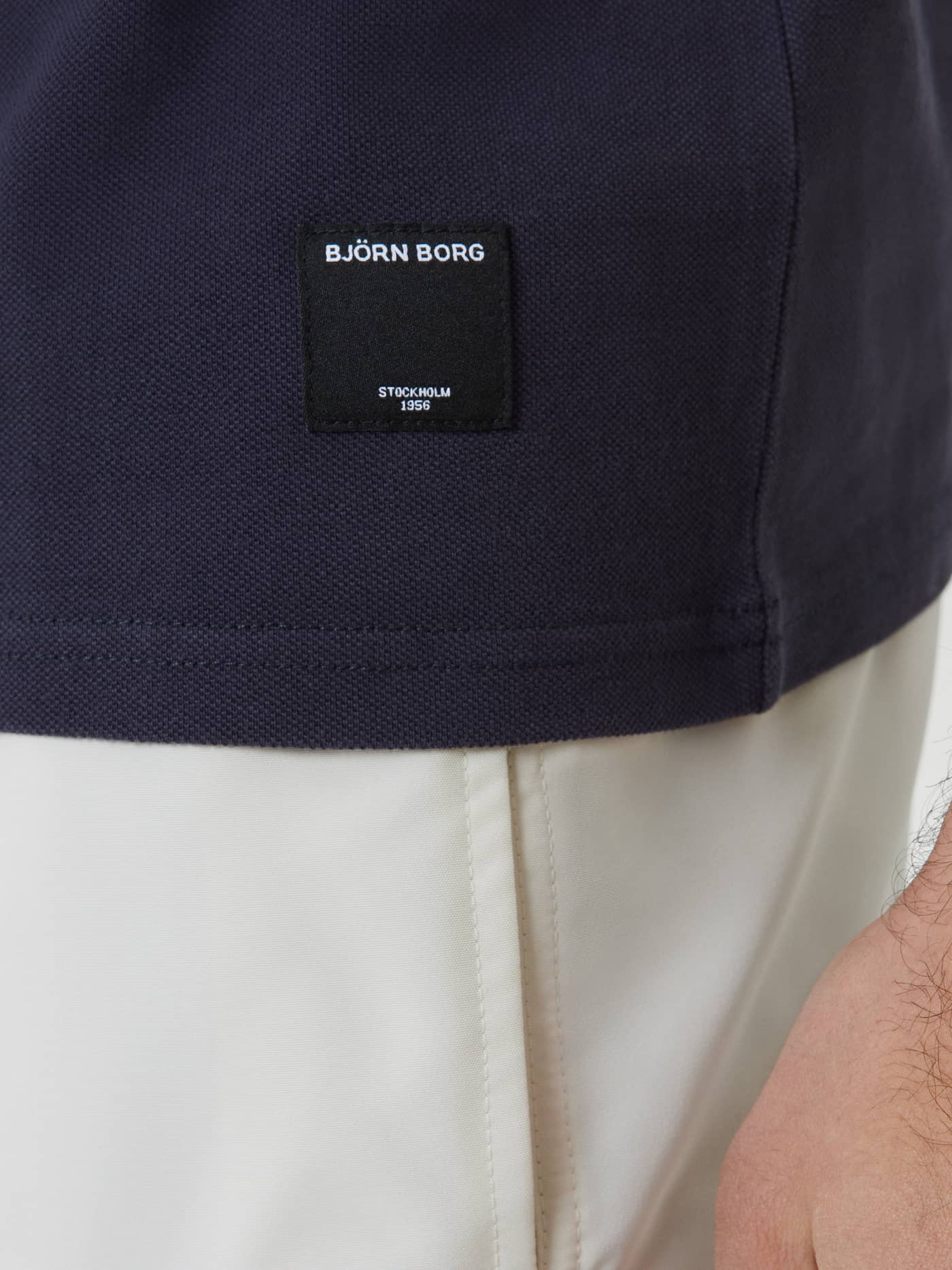 Close-up of the Borg Polo Shirt in Night sky (Navy) featuring a black woven logo label on textured cotton piqué. - Image 4