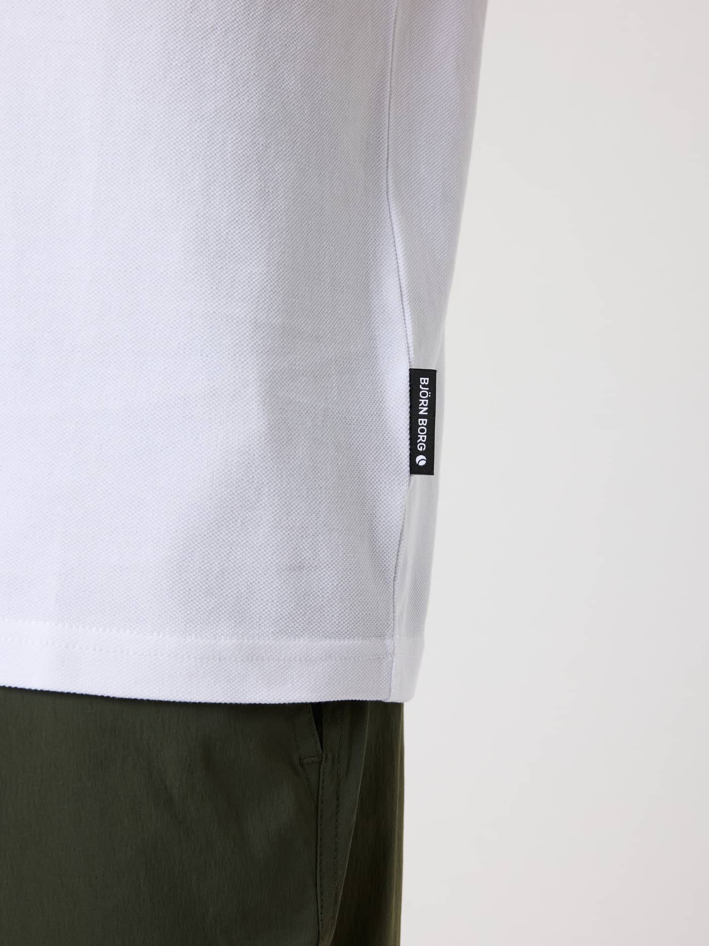 Nahaufnahme des Borg Polo Shirt in Brilliant White (Weiß) aus Baumwoll-Piqué mit seitlichem Flag-Label. - Image 4