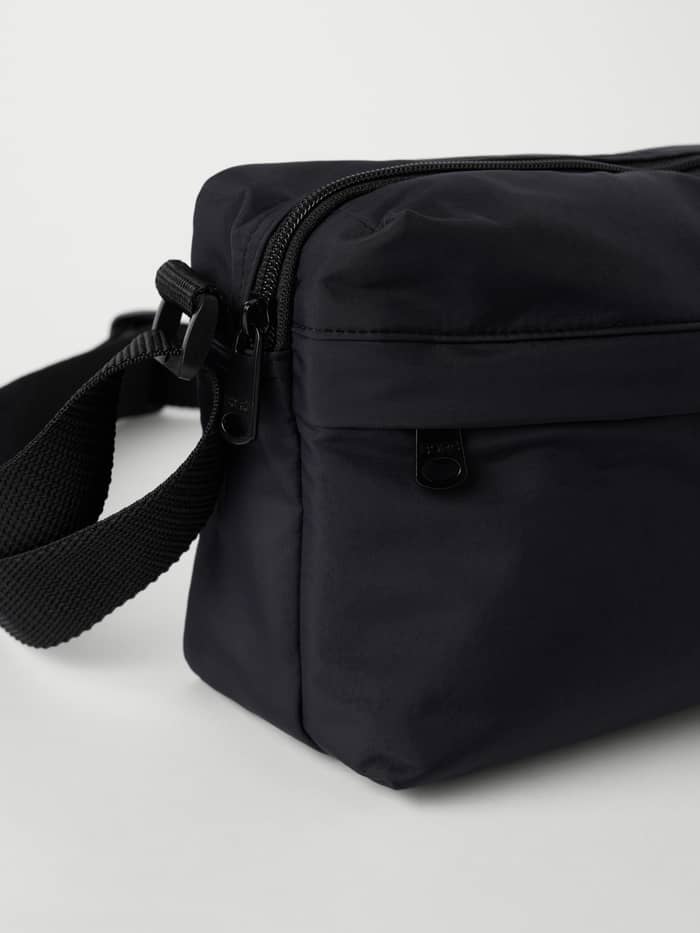 Studio Active Crossover Bag in Black Beauty (Zwart) van gerecycled polyester met zwarte logo-ritsen, close-up. - Image 2