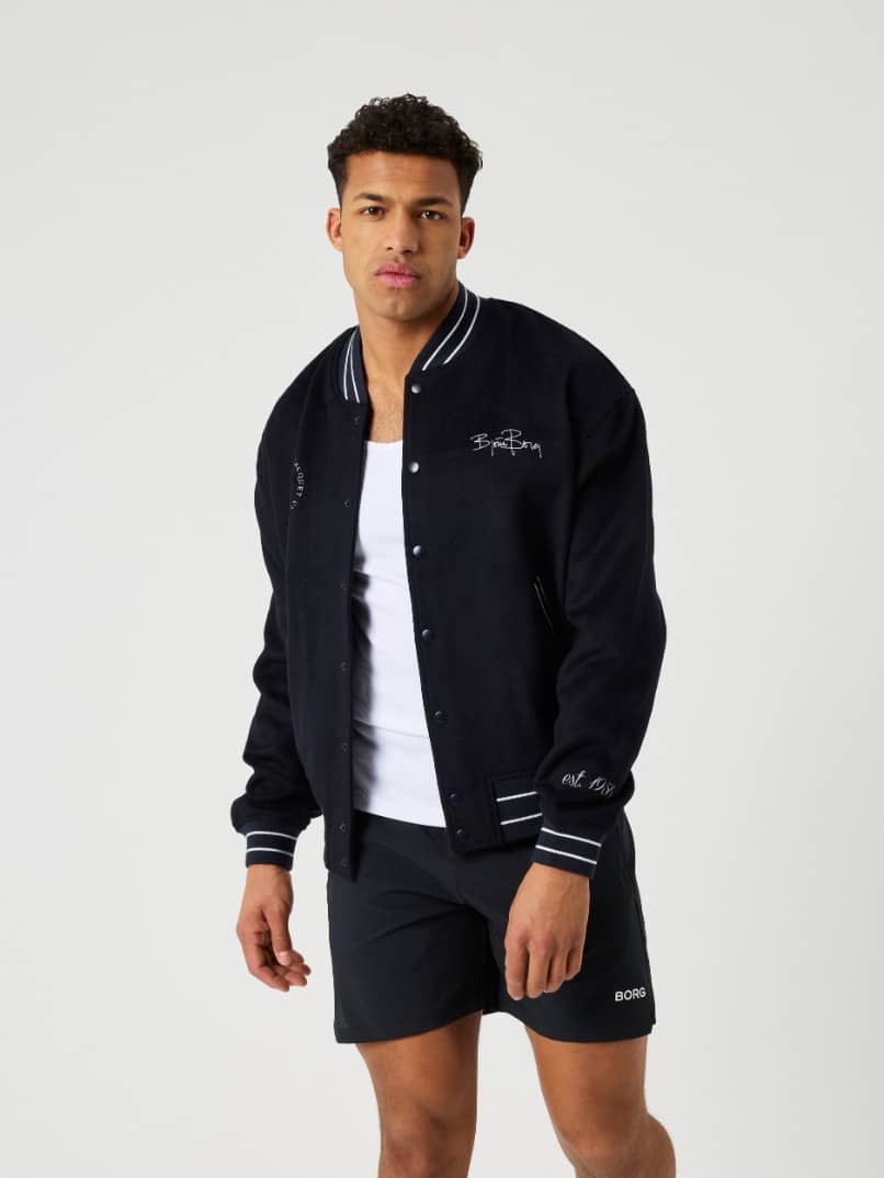 Borg Varsity Jacket in Night sky (Marineblauw) van wolvilt op een man in vooraanzicht voor een tennis-geïnspireerde stijl. - Image 1
