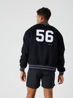 Vue de dos d'un homme en Borg Varsity Jacket oversize Night sky (Marine) en laine, logo blanc et style tennis. - Image 2