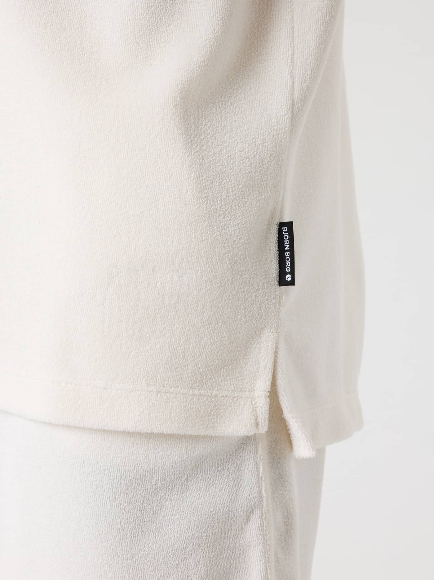 Detailed side view of the Borg Toweling Pool Shirt in Tofu (White) featuring a side slit and black Björn Borg logo label. - Image 4
