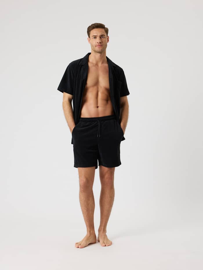 Vorderansicht eines Mannes im Borg Toweling Pool Shirt in Black Beauty (Schwarz) aus weichem Frottee-Material. - Image 3