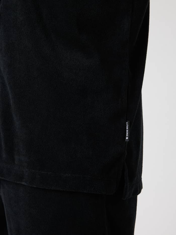 Nahaufnahme des Borg Toweling Pool Shirt für Herren in Black Beauty (Schwarz) aus Frottee mit Seitenschlitz und weißem Logo. - Image 4