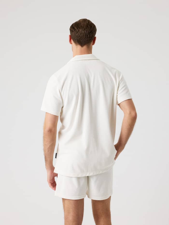 Rückansicht eines Mannes im Borg Toweling Pool Shirt in Tofu (Weiß) aus weichem Frottee mit schwarzem Logo-Label. - Image 2