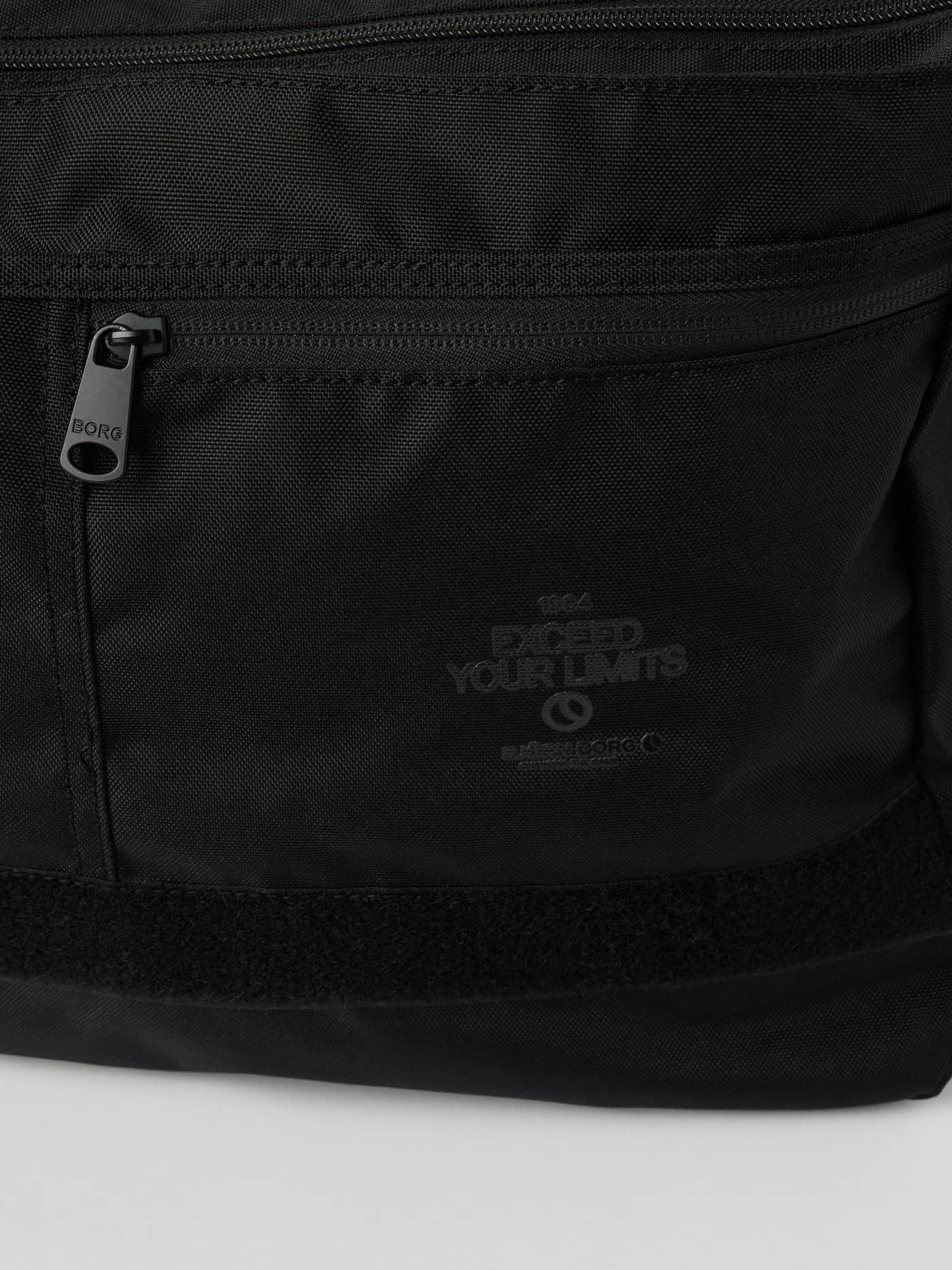 Detailansicht der Core Flapbag 12,5L in Black Beauty (Schwarz) mit Logo-Reißverschluss und tonalen Grafik-Prints. - Image 4