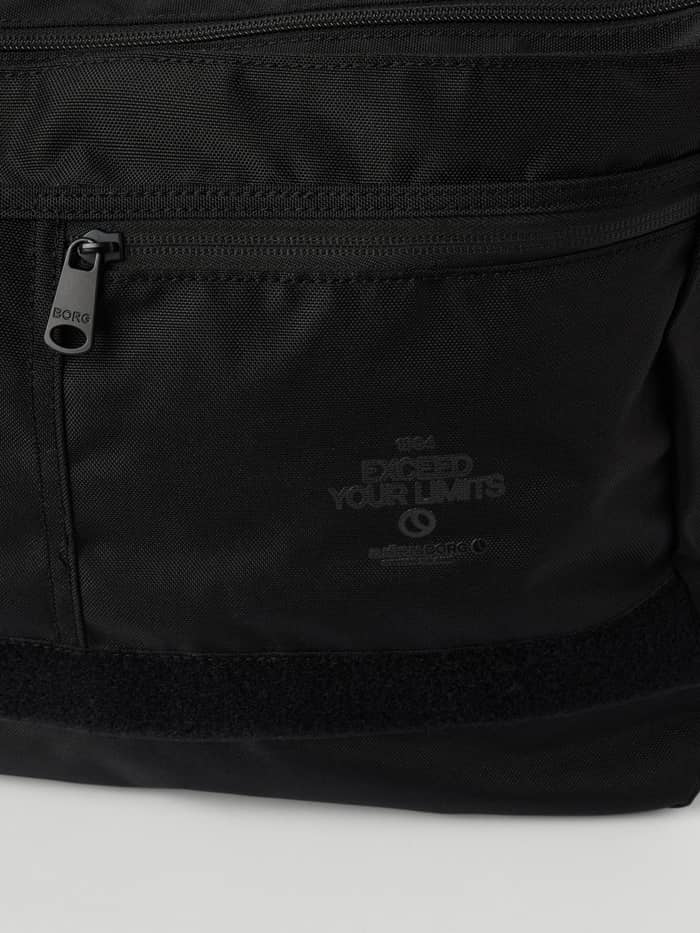 Détail du Core Flapbag 12,5L en Black Beauty (Noir) avec fermeture éclair à logo et graphismes ton sur ton. - Image 4