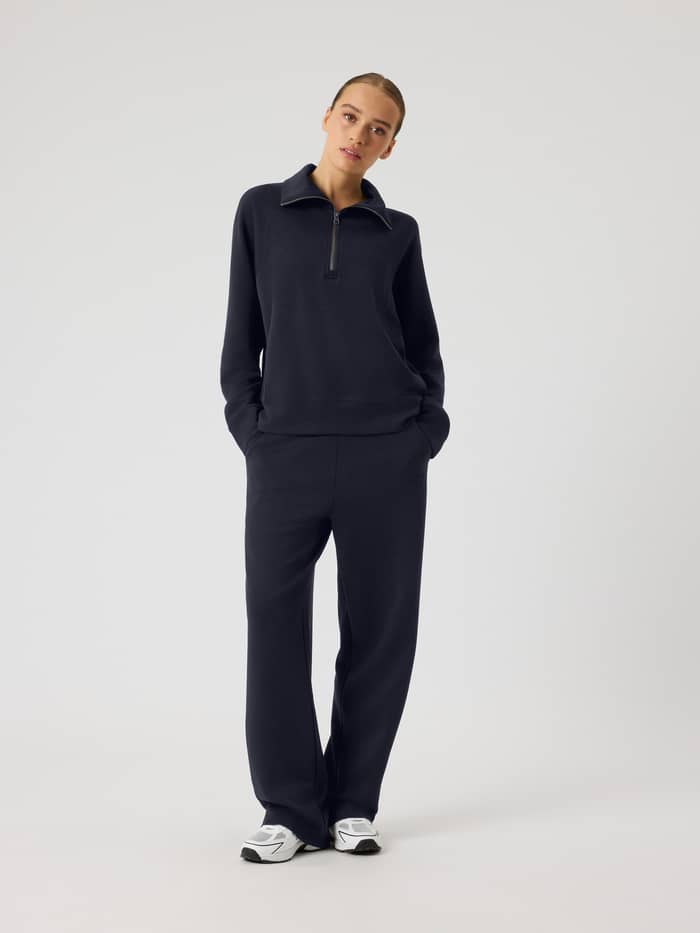 Full-body front view of a woman wearing the loose fit Studio Soft Halfzip Sweatshirt in Night sky (Navy) for tennis.