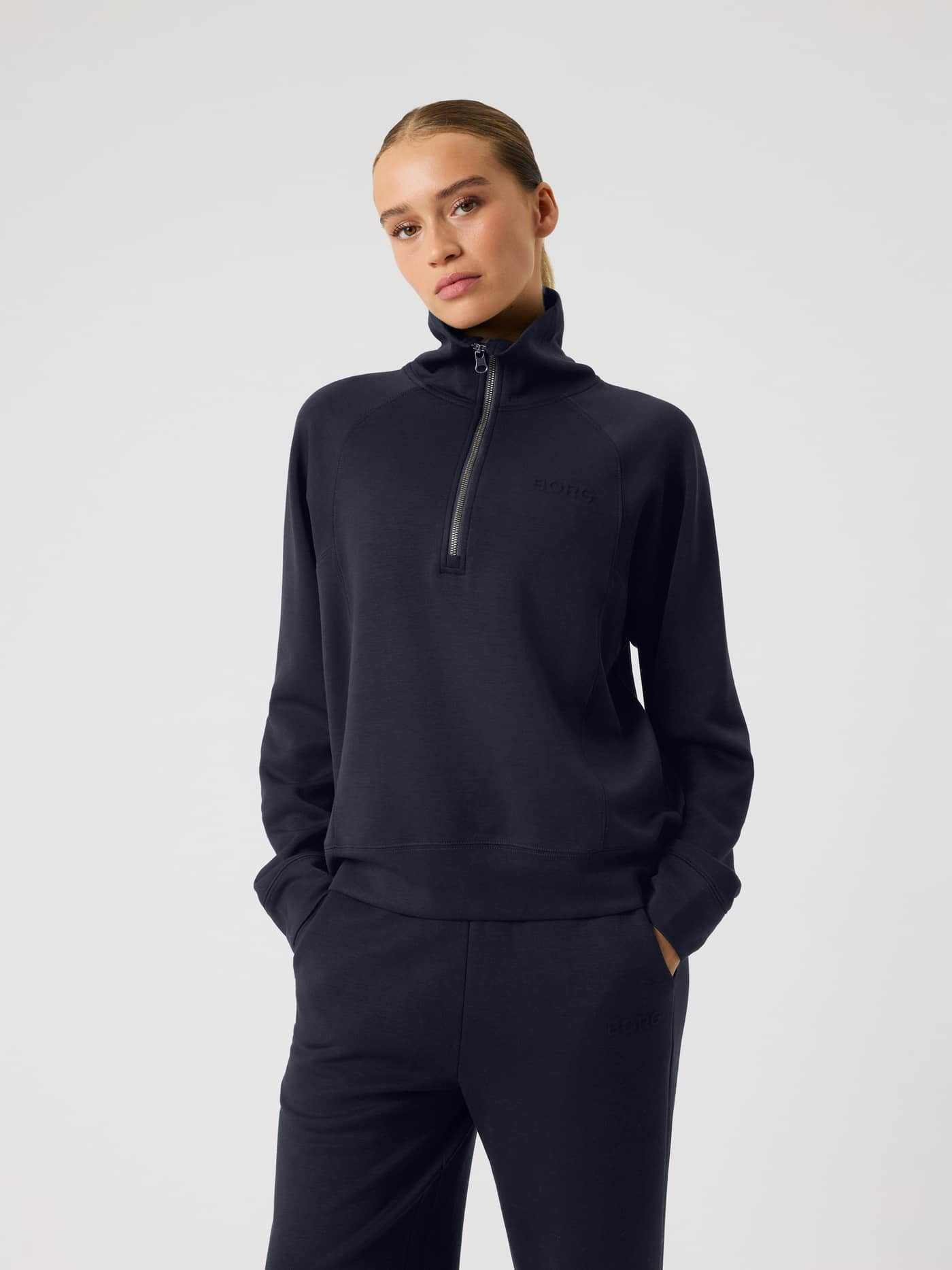 Front view of a woman wearing the Studio Soft Halfzip Sweatshirt in Night sky (Navy) with a tonal logo and loose, soft feel. - Image 1