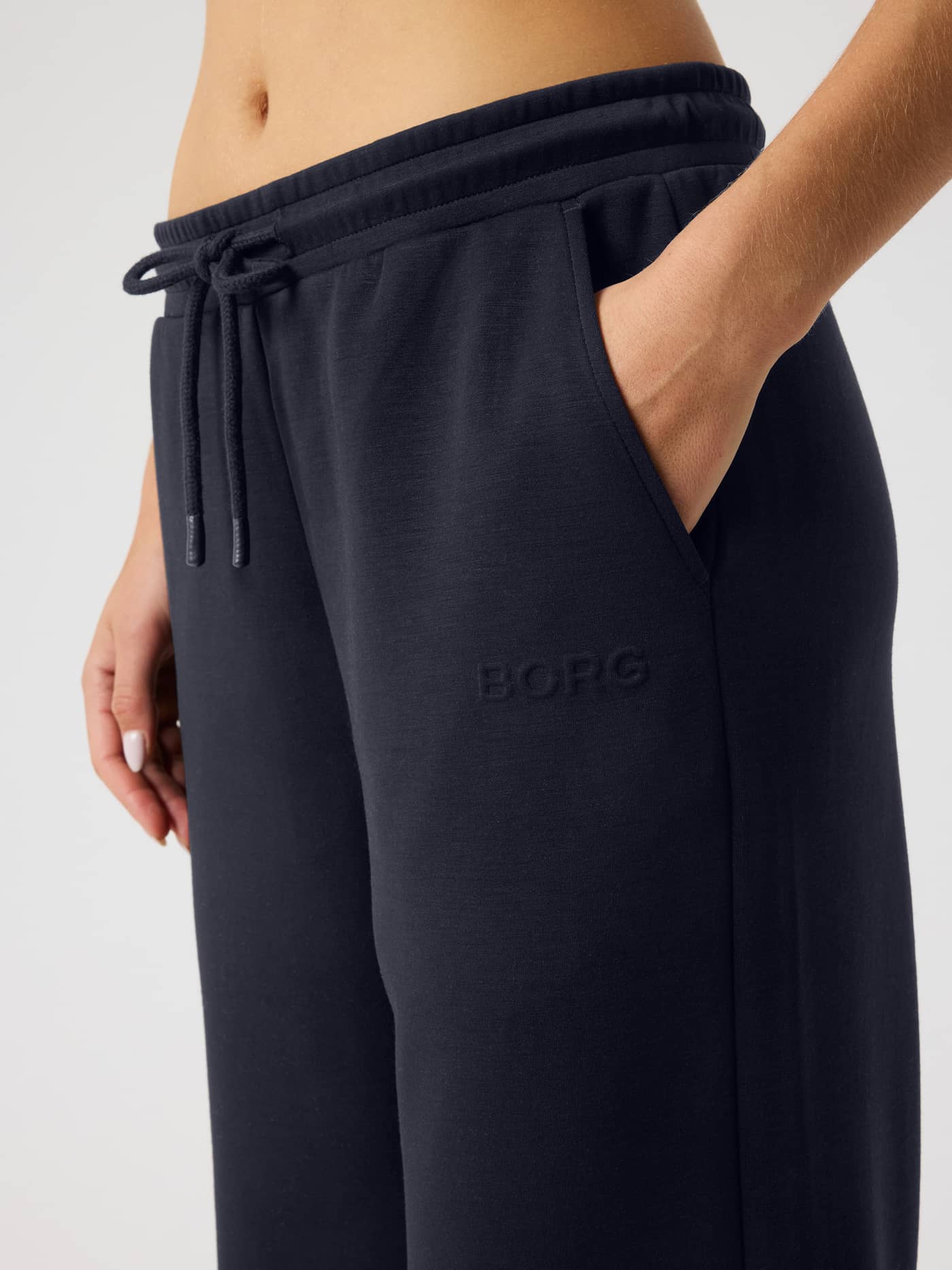 Close-up of a model wearing the Night sky (Navy) Studio Soft Sweatpants featuring a drawstring and a navy BORG logo. - Image 5
