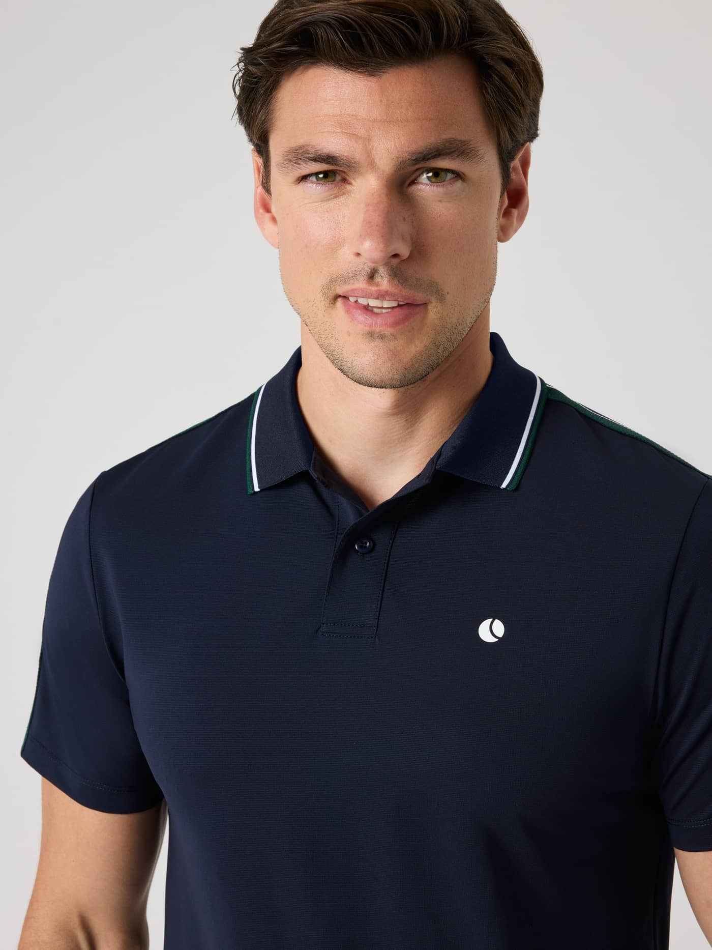 Close-up front view of a man in the Ace Retro Polo Shirt in Night sky (Navy), with a white logo for tennis performance. - Image 4