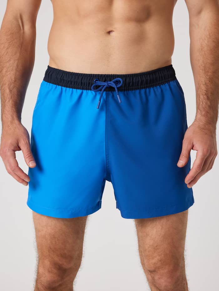 Front view of a man wearing the Borg Blocked Swim Shorts in Palace Blue (Blue), featuring a functional, paneled design.