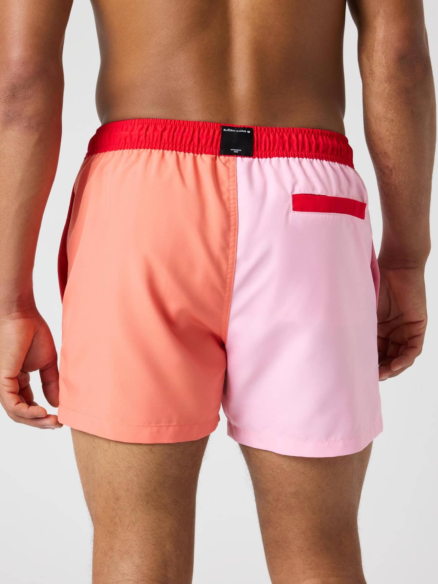 Back view of a man wearing the stylish Björn Borg Blocked Swim Shorts in Candy Pink (Pink) with a functional rear pocket. - Image 2
