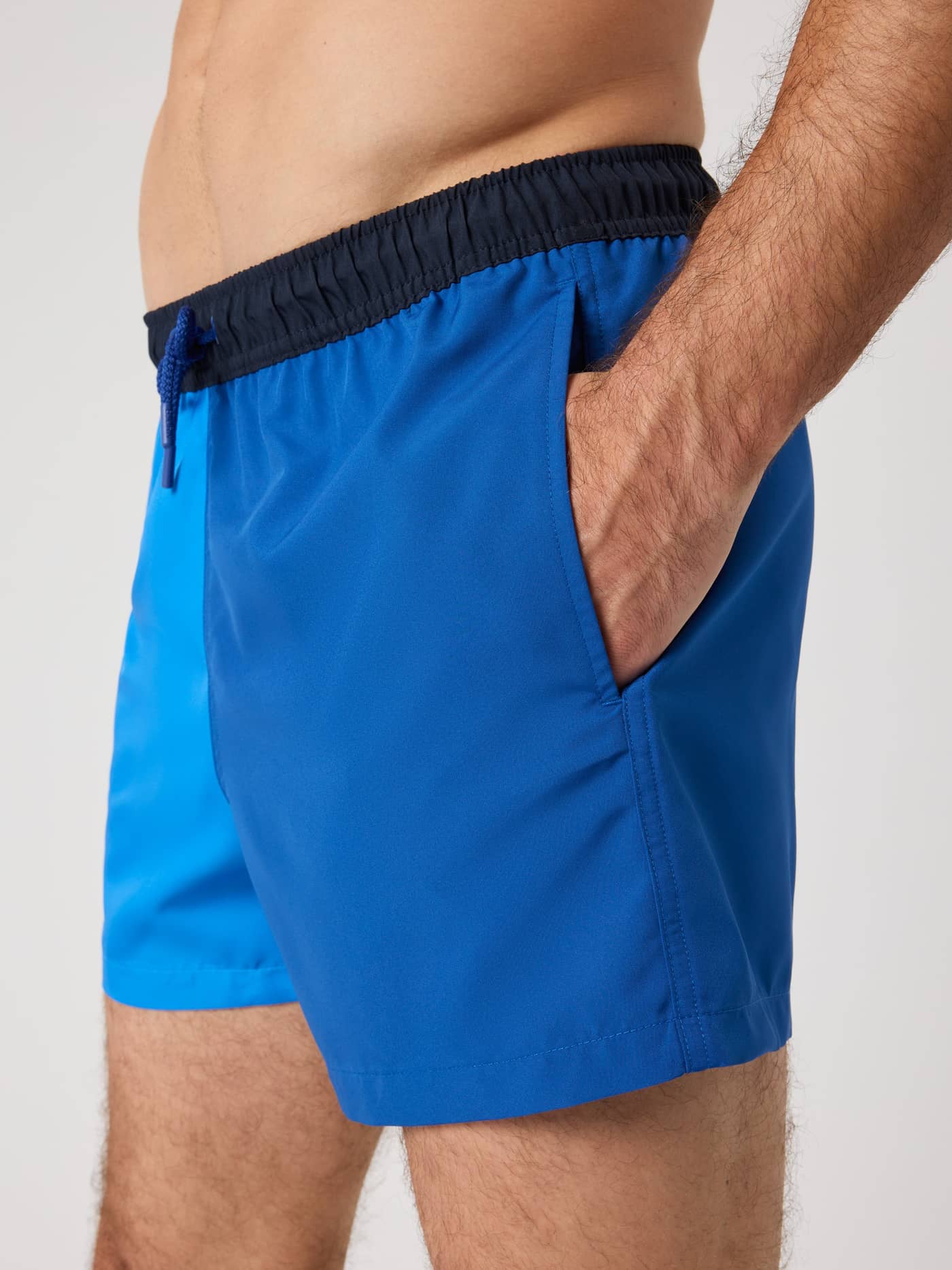 Side view of a model wearing Björn Borg Blocked Swim Shorts in Palace Blue (Blue) featuring a functional side pocket. - Image 4