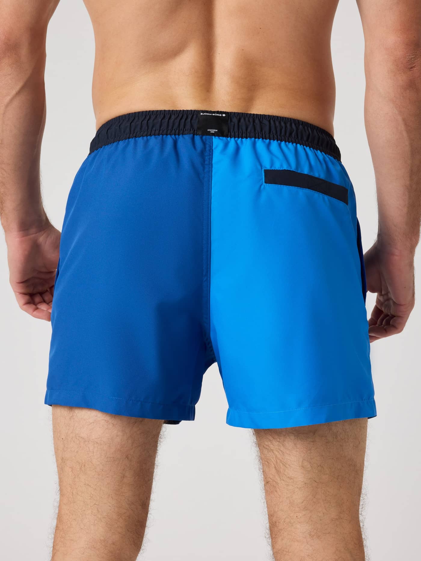 Back view of a man in Palace Blue (Blue) Björn Borg Blocked Swim Shorts with quick-drying fabric and a secure back pocket. - Image 2