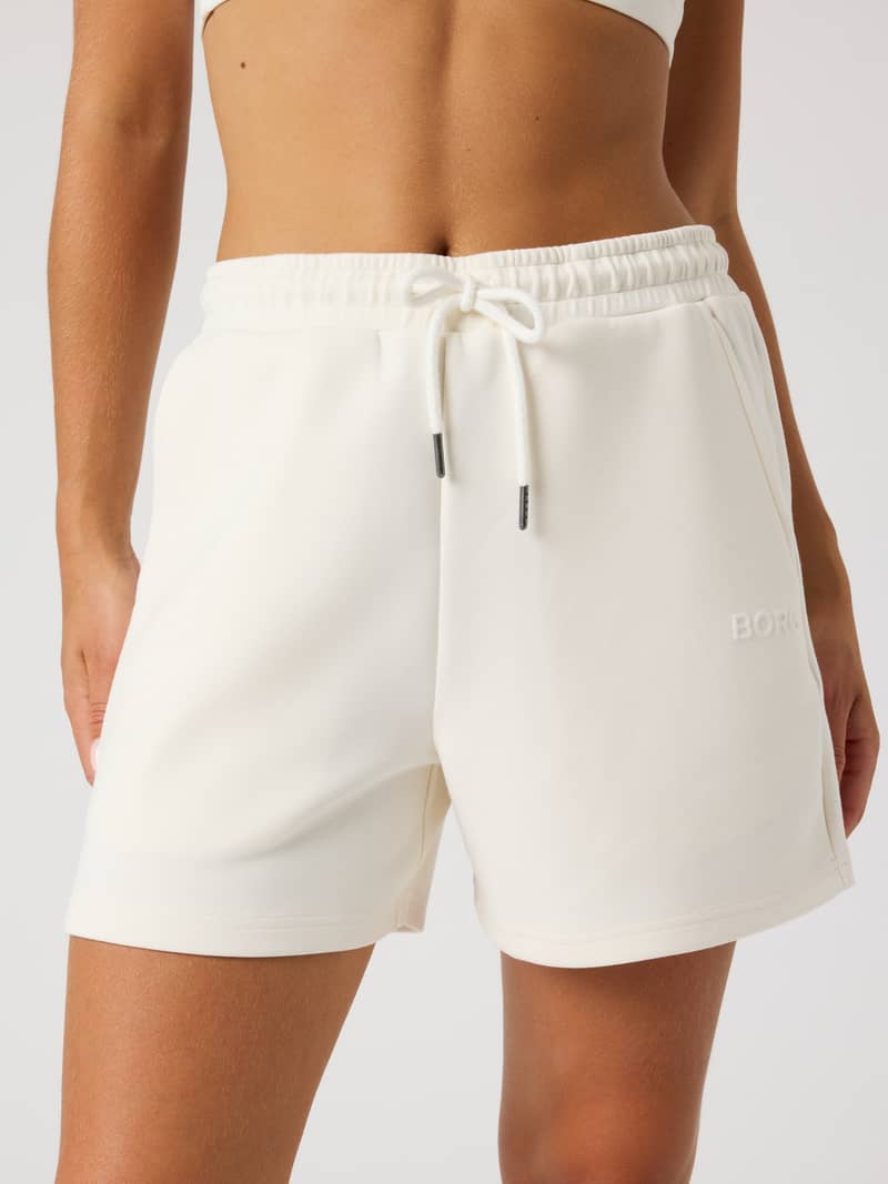 Vue de face du Studio Soft Sweatshorts en Tofu (Blanc), coupe ample, taille à cordon de serrage et logo blanc pour femme.