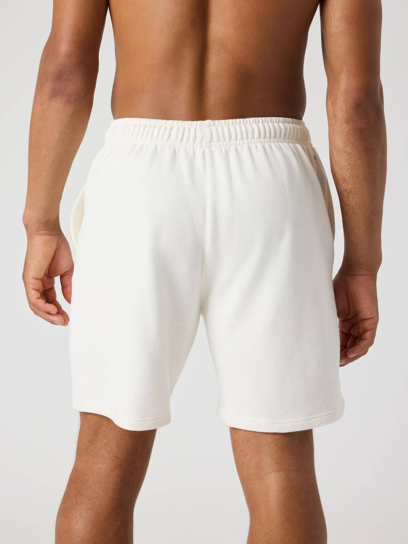 Vista posterior de un hombre con los Borg Classic Sweatshorts en Tofu (Blanco) y detalle de pelota de tenis. - Image 2
