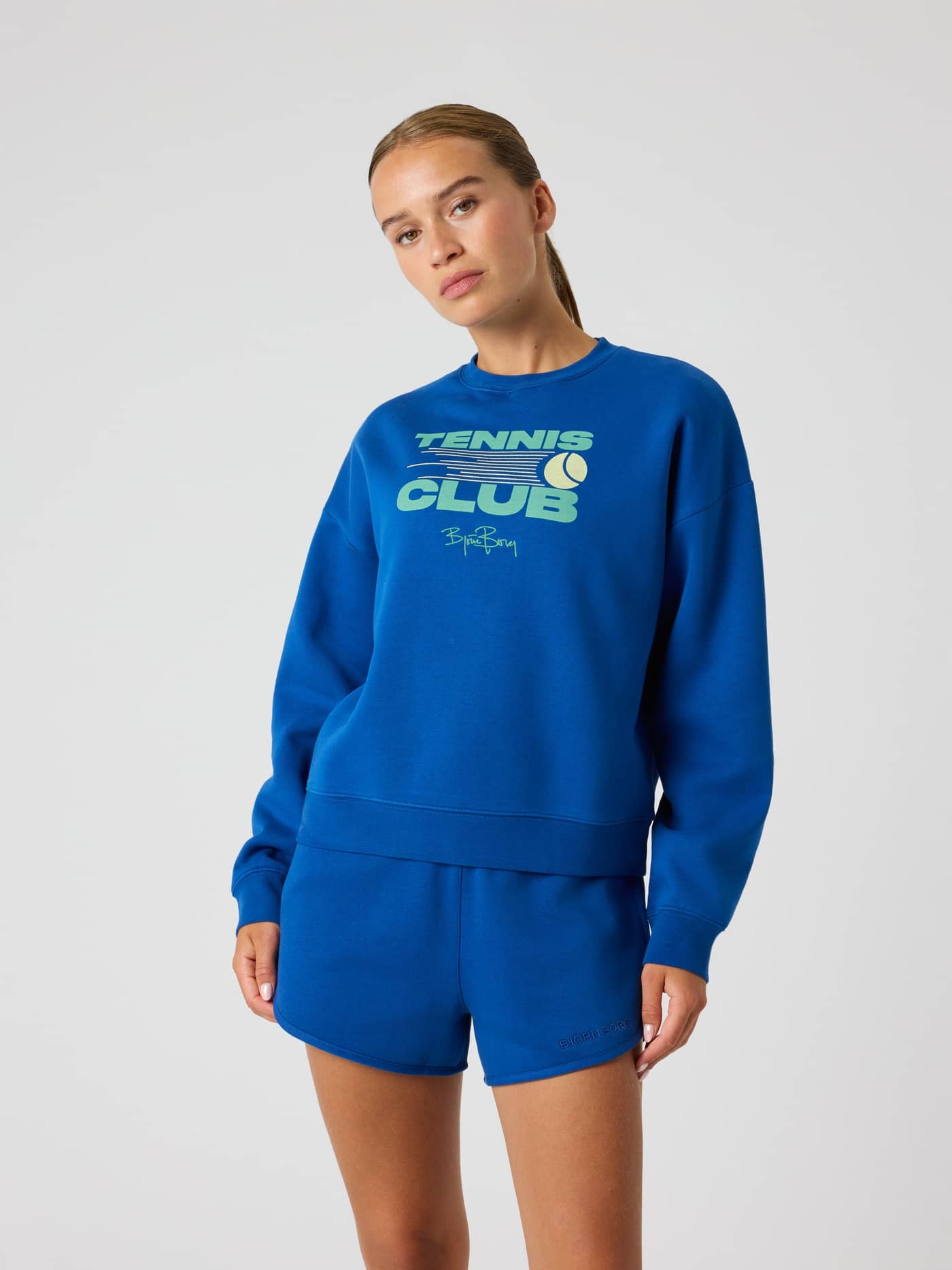Front view of a model wearing the Monaco Blue (Blue) Borg Boyfriend Sweatshirt with a tennis chest print. - Image 2