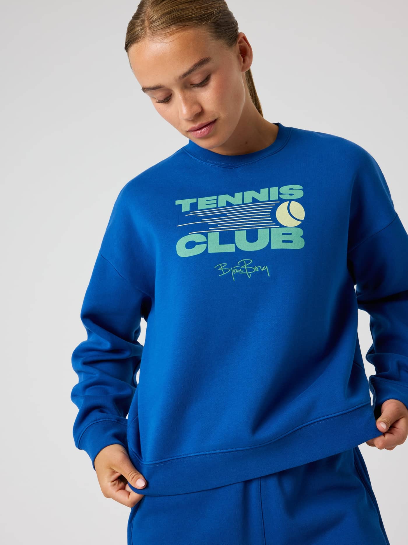 Front view of a woman wearing the oversized Borg Boyfriend Sweatshirt in Monaco Blue (Blue) with a tennis club graphic. - Image 6