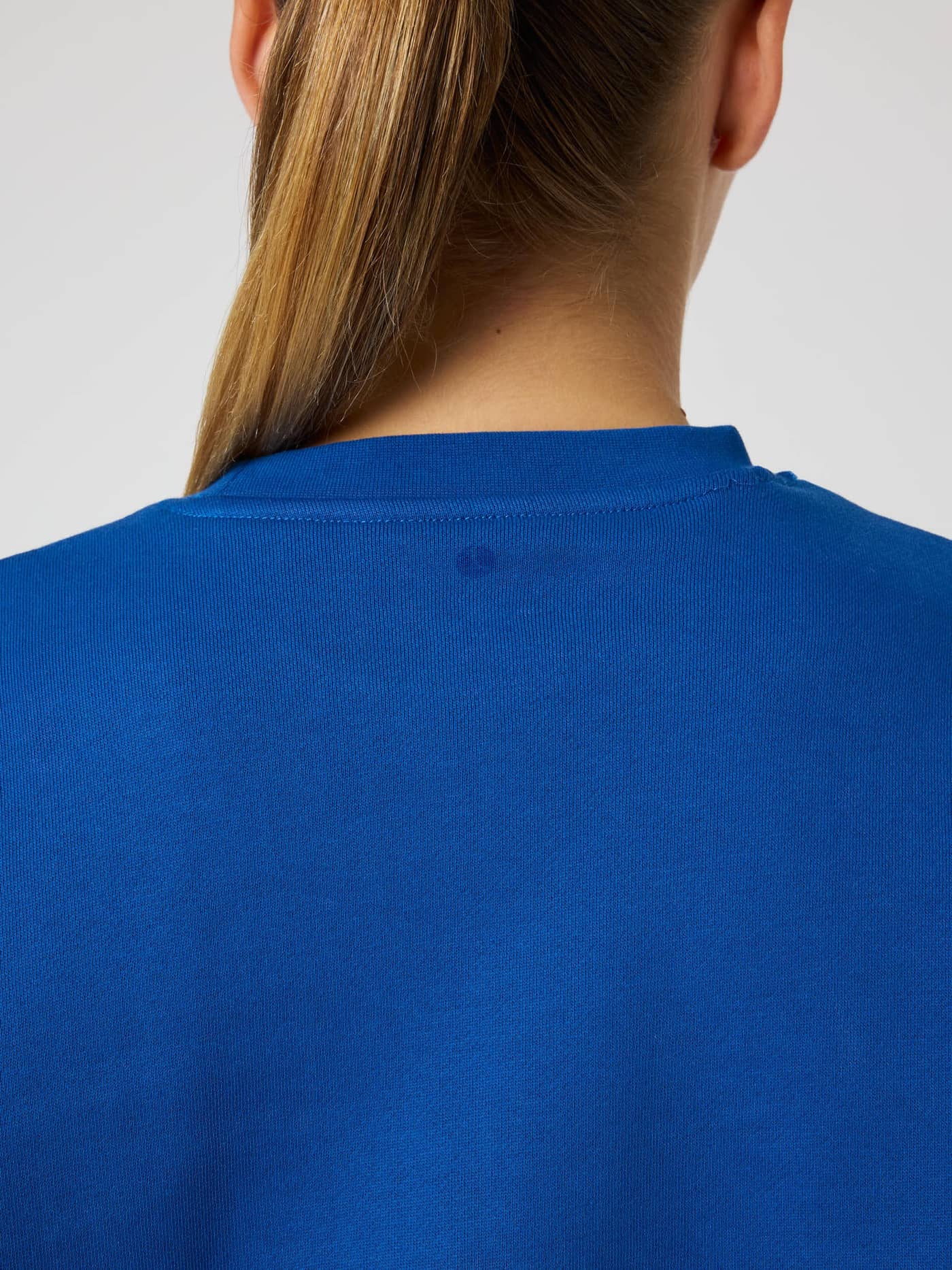 Detailed close-up of the back neck on the Monaco Blue (Blue) Borg Boyfriend Sweatshirt with a tennis ball print. - Image 5