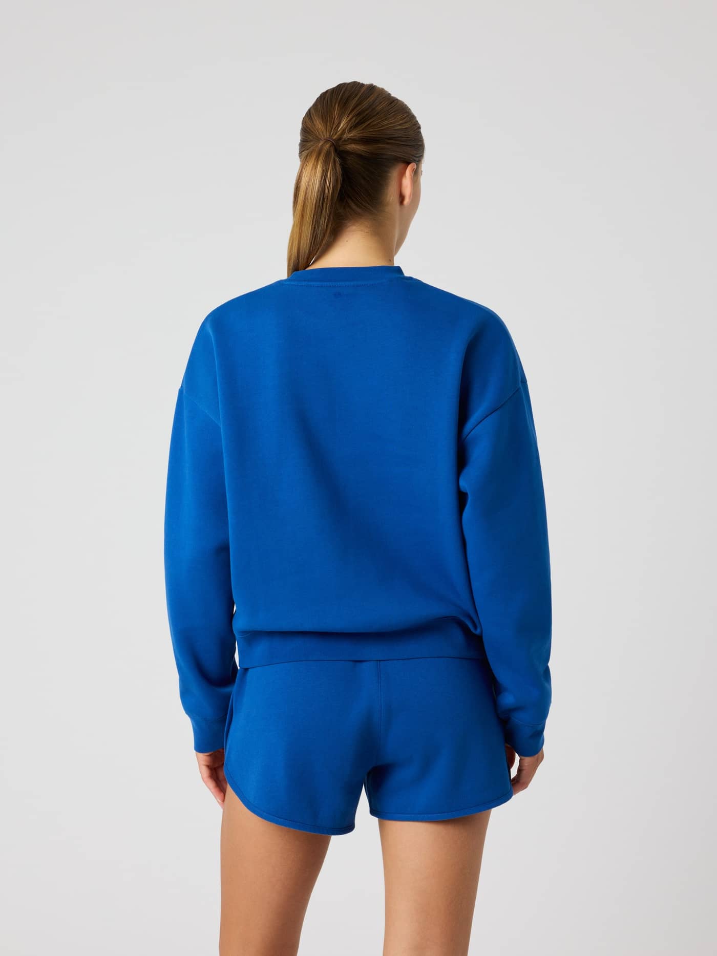 Back view of a woman wearing the oversized Björn Borg Boyfriend Sweatshirt in Monaco Blue (Blue) with a tennis print. - Image 3