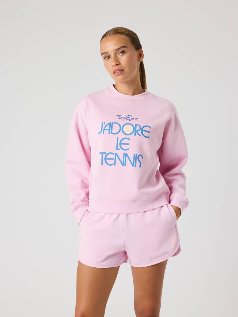 Vista frontal de una modelo con la Borg Boyfriend Sweatshirt en Pink Lady (Rosa) con gráfico de tenis y ajuste oversized.