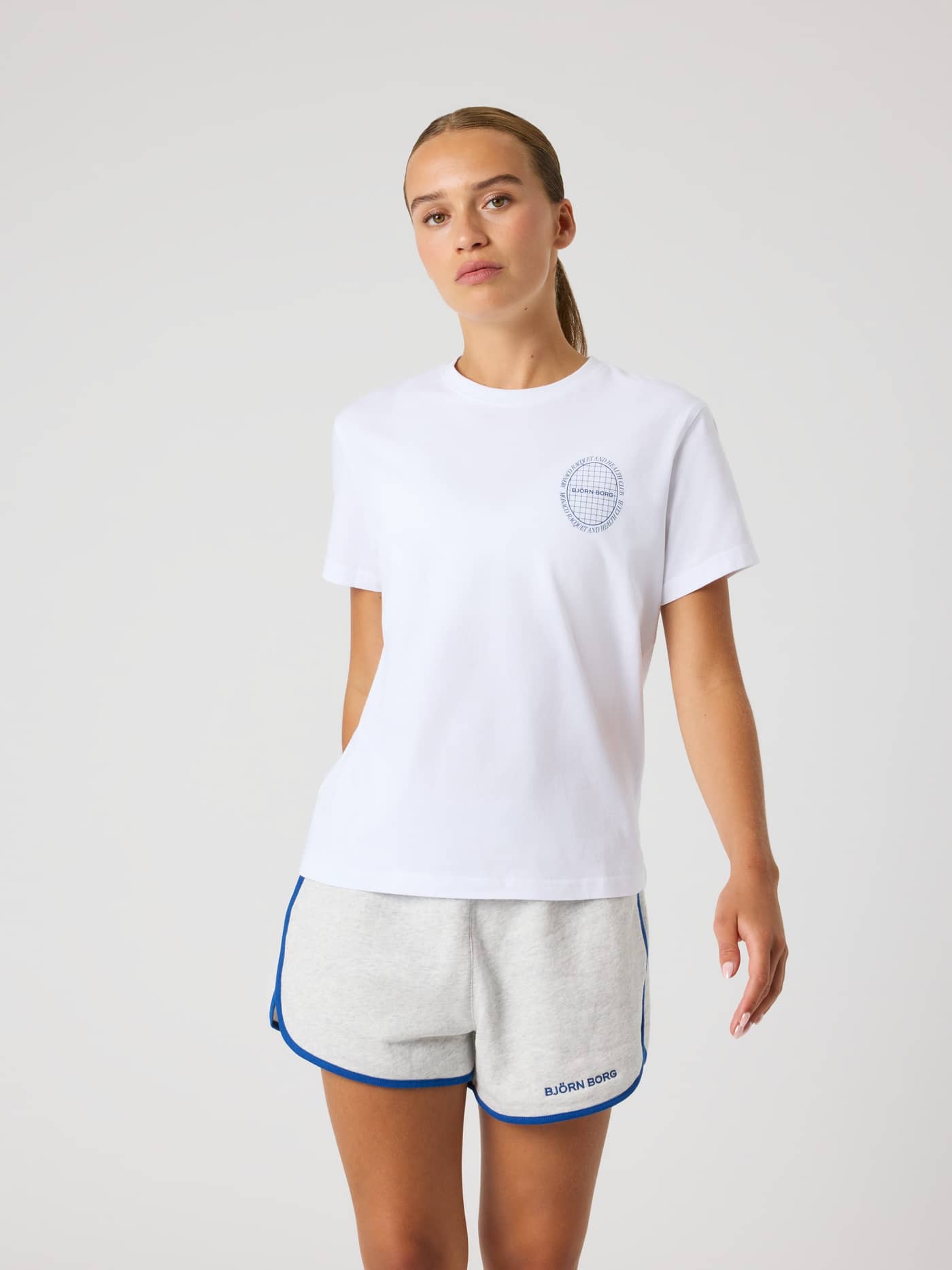 Front view of a woman in the regular fit Borg Cotton T-Shirt in Brilliant White (White) with a blue tennis chest logo. - Image 3