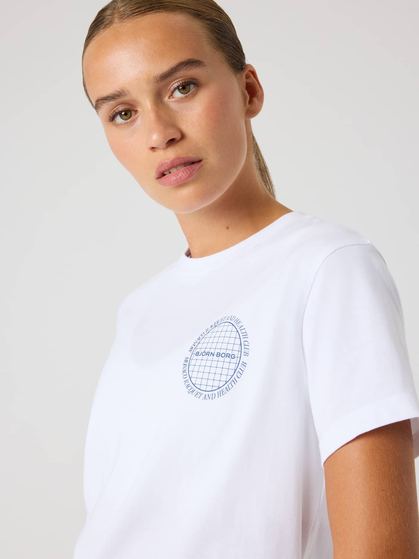 Close-up of a woman in the cotton Borg Cotton T-Shirt in Brilliant White (White) with a stylish blue tennis chest logo. - Image 2
