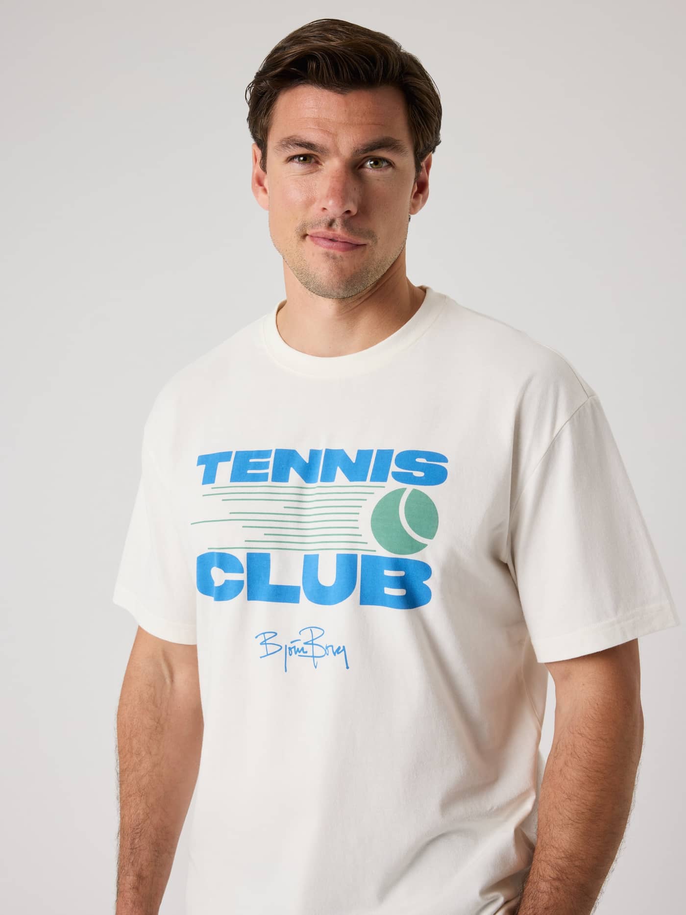 Front view of a man wearing the cotton Borg Classic Print T-Shirt in Tofu (White) featuring a tennis chest graphic. - Image 6
