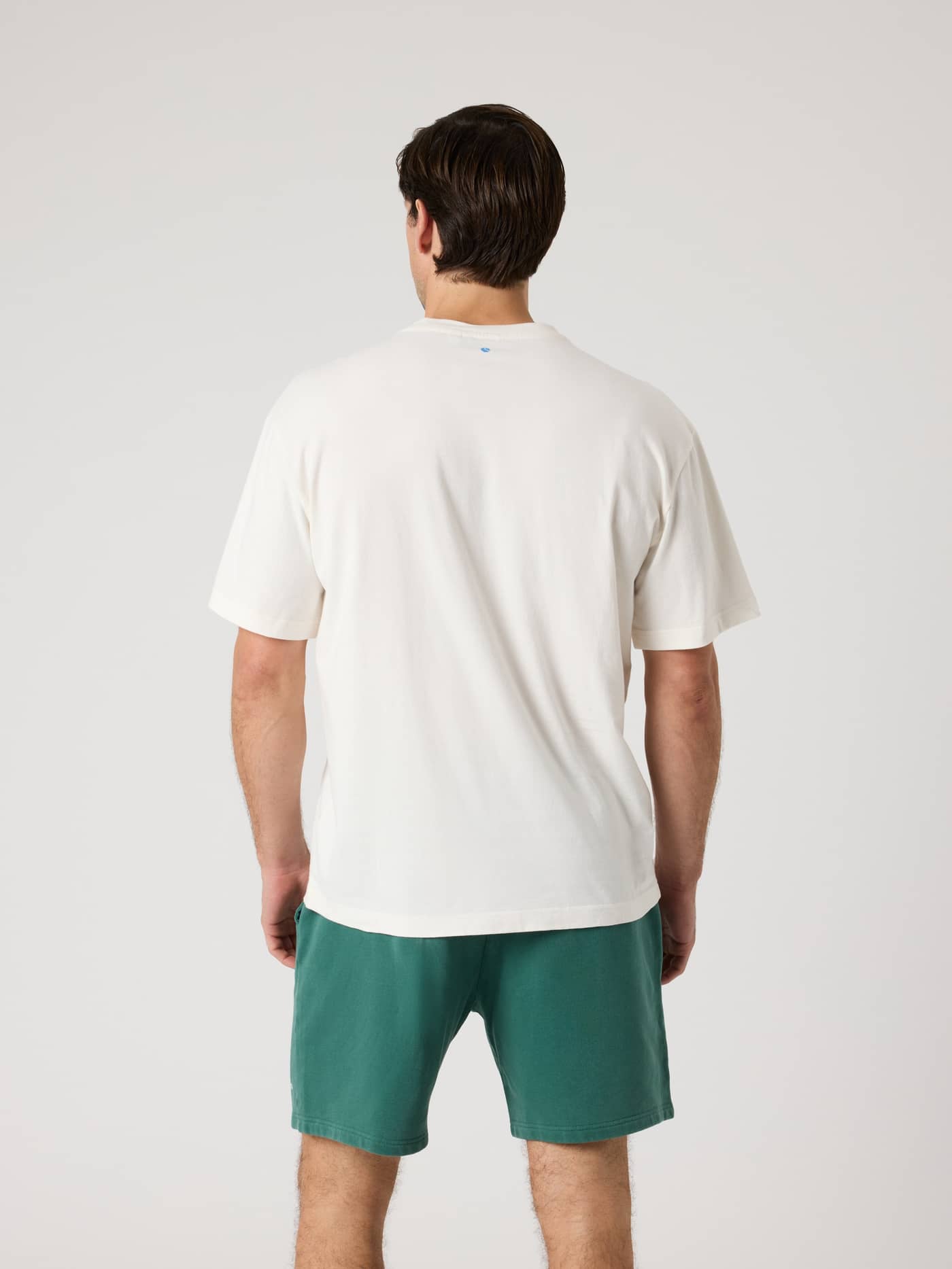 Back view of a man wearing the cotton Borg Classic Print T-Shirt in Tofu (White) featuring a tennis ball print. - Image 3