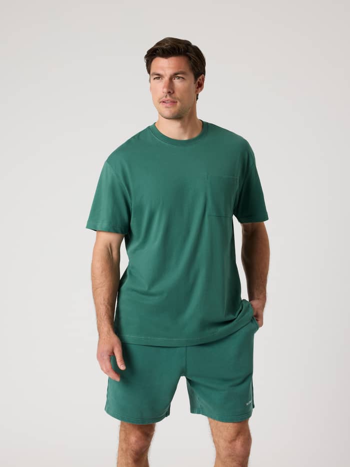 Front view of a man wearing the Borg Relaxed T-shirt in Mallard Green, featuring a chest pocket and matching shorts.