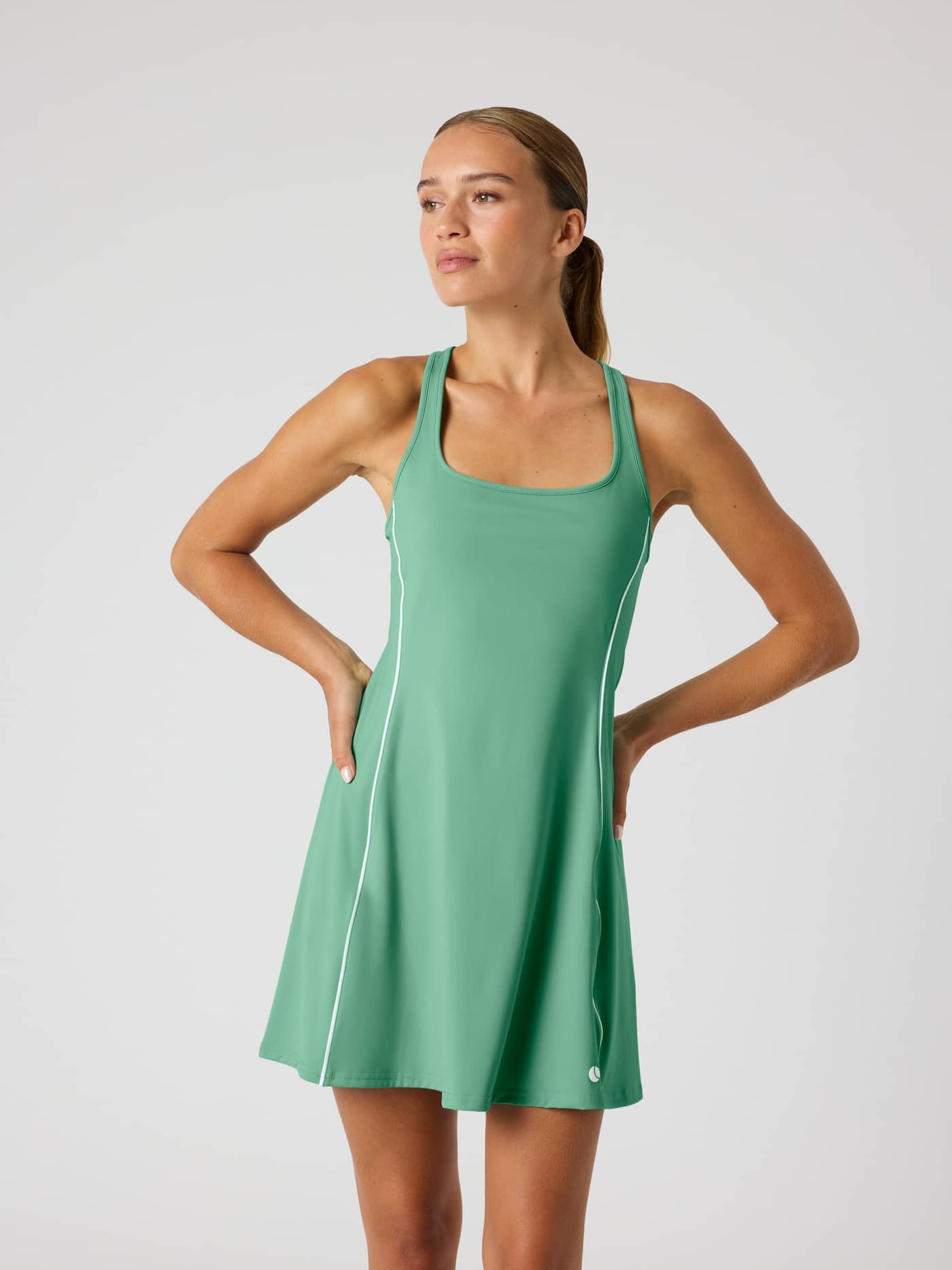 Ace Scooped Racerback Dress in Malachite Green (Groen), een slim fit tennisjurk met wit logo in vooraanzicht. - Image 1