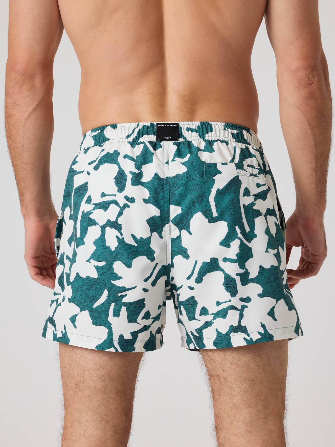 Back view of a man wearing the Björn Borg Print Swim Shorts in a green and white digital print for style and function. - Image 2