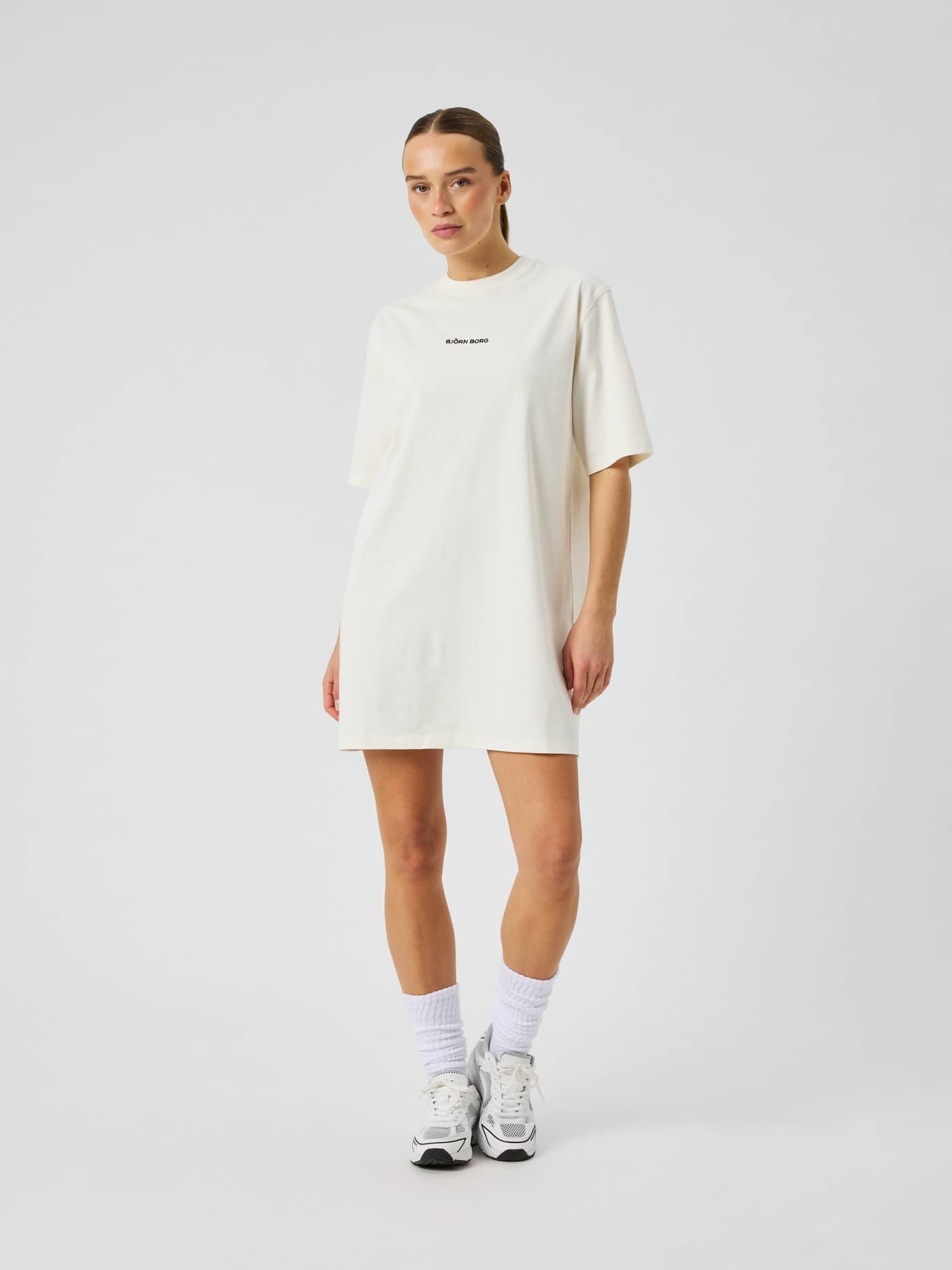 Vue de face de la Studio Oversized T-Shirt Dress en coton Tofu (Blanc) avec coupe ample et logo noir. - Image 4