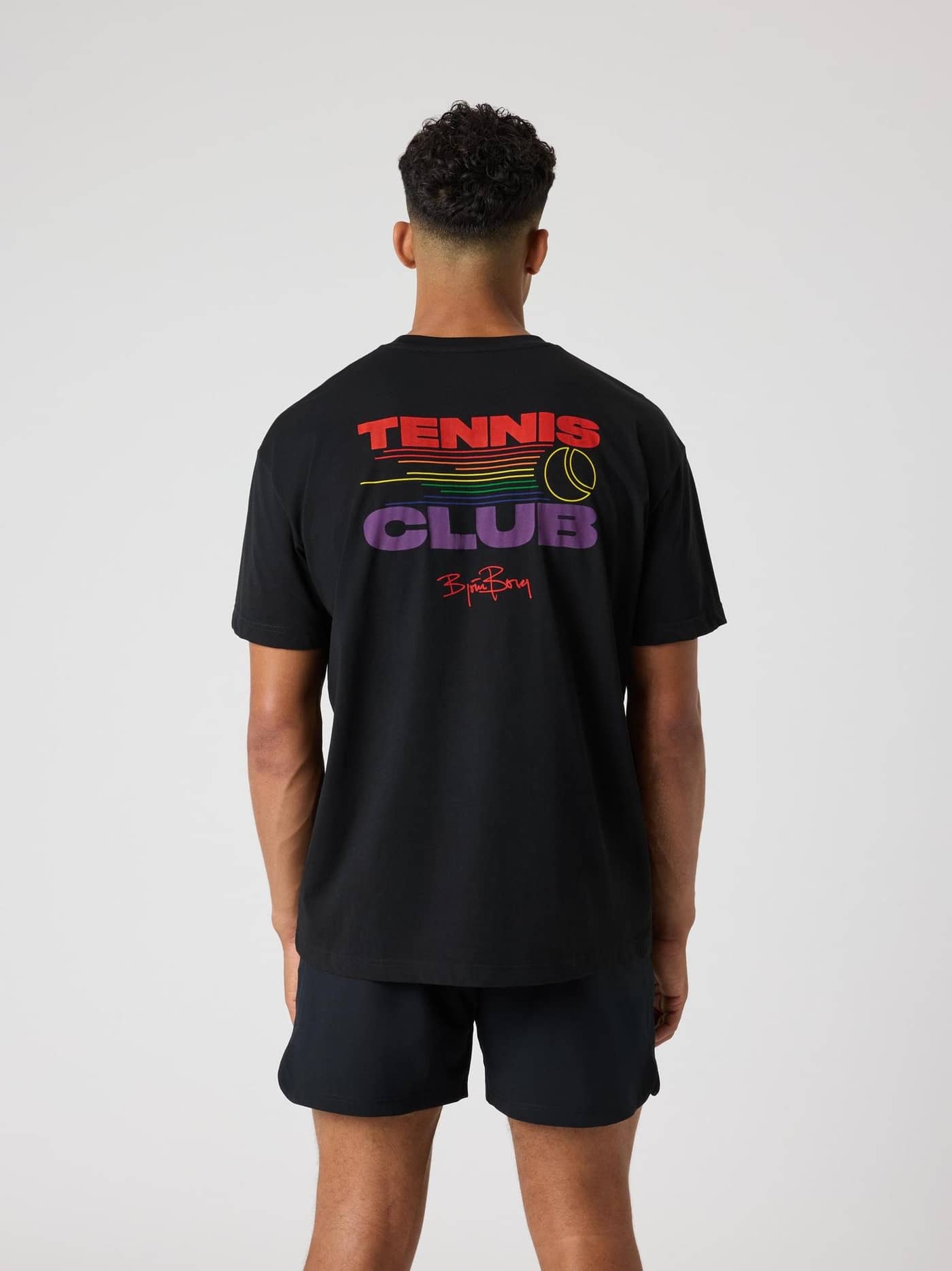 Achteraanzicht van een man in het Black Beauty (Zwart) Borg Gym Pride Oversized T-Shirt met tennisgraphic voor training. - Image 1