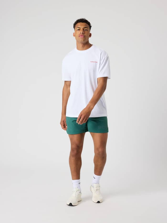 Vooraanzicht van een man in het Borg Gym Pride Oversized T-Shirt in Brilliant White (Wit) met rood logo voor training. - Image 4