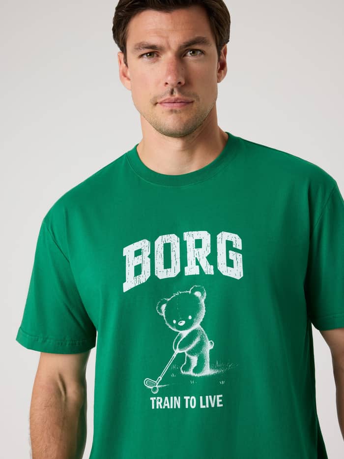 Front view of a man in the Björn Borg Classic Print T-Shirt in Verdant Green (Green) with a white golf and training print.