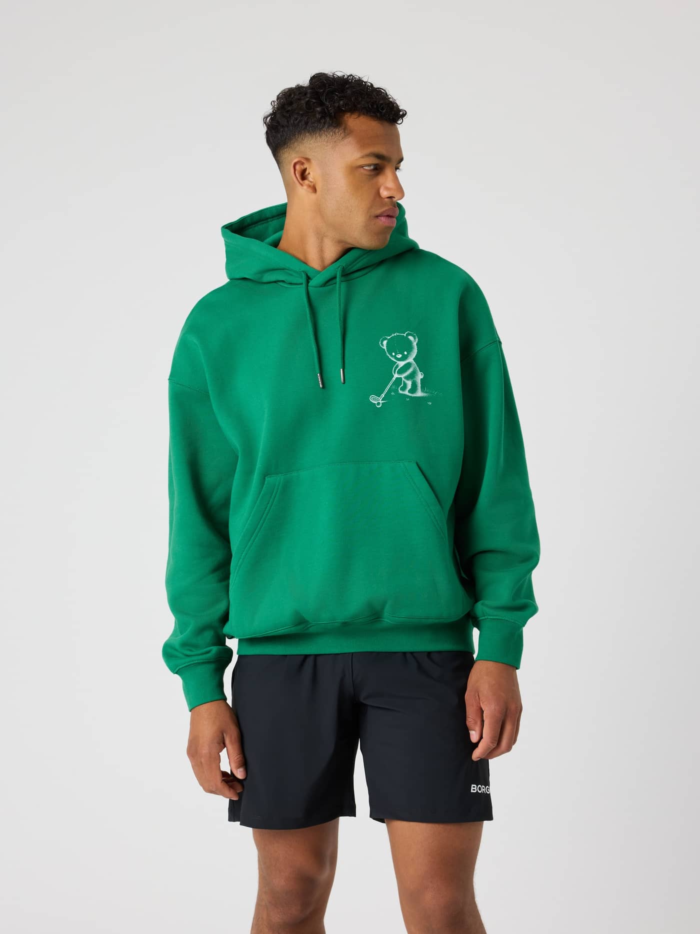 Vista frontal de un hombre con la Borg Oversized Hoodie en Verdant Green (Verde) de algodón y gráfico de oso de golf. - Image 2