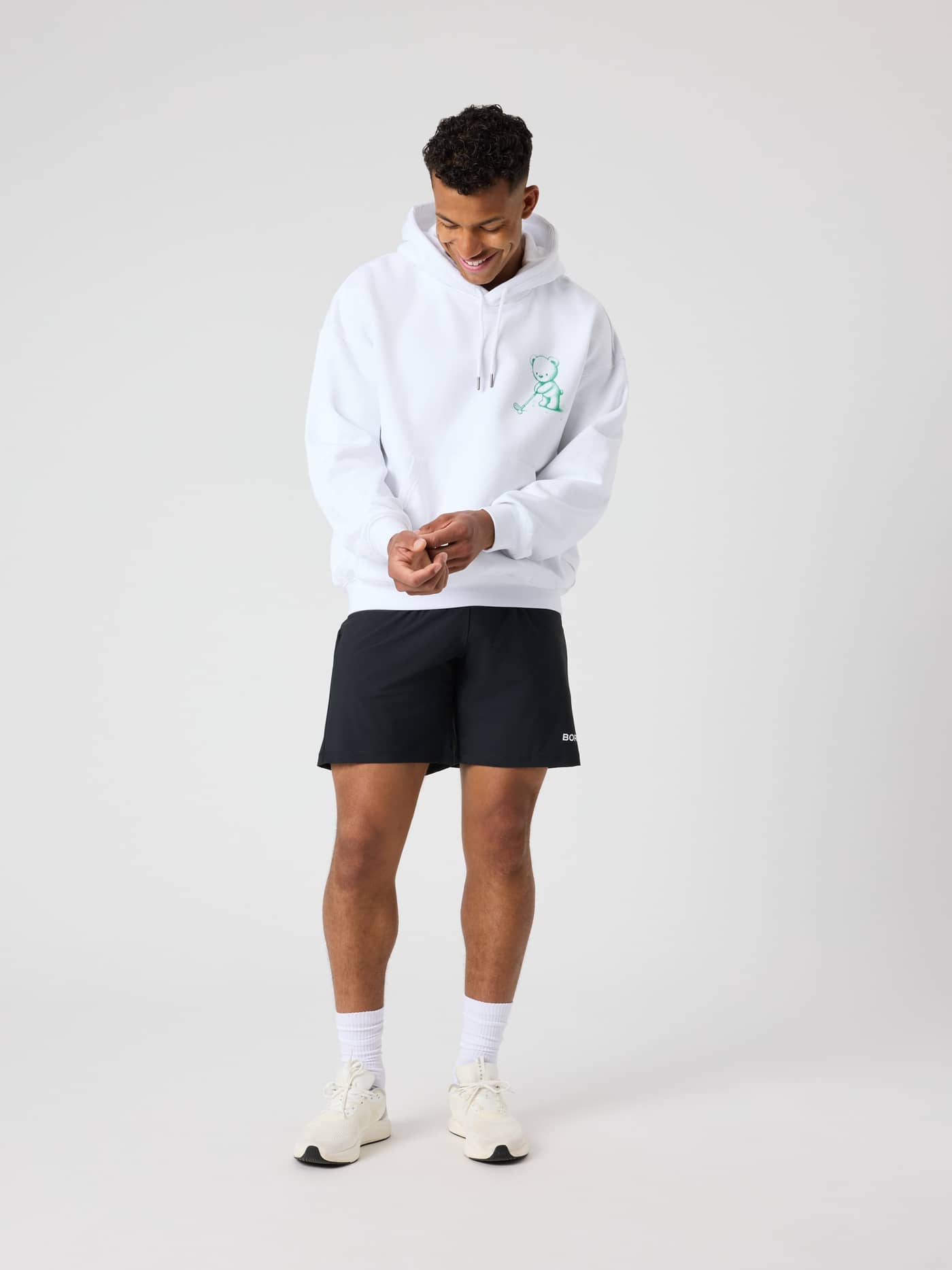 Ganzkörperansicht eines Mannes im Borg Oversized Hoodie in Brilliant White (Weiß) mit einer grünen Golf-Grafik. - Image 4