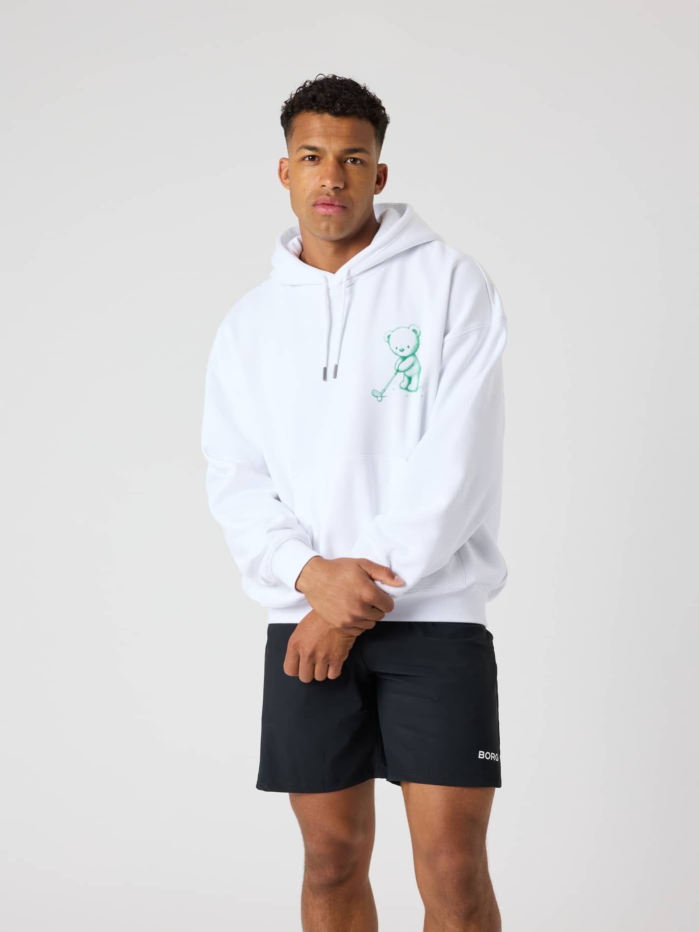 Vorderansicht eines Mannes im Borg Oversized Hoodie in Brilliant White (Weiß) aus Baumwollmix mit grüner Golf-Grafik. - Image 2