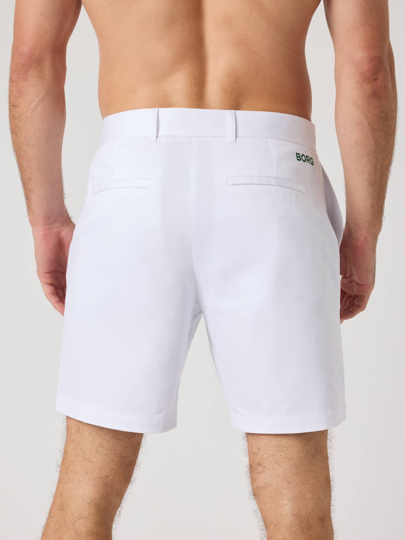 Back view of a man wearing the Borg Golf Chinos Shorts in Brilliant White (White) with a green logo for golf performance. - Image 2