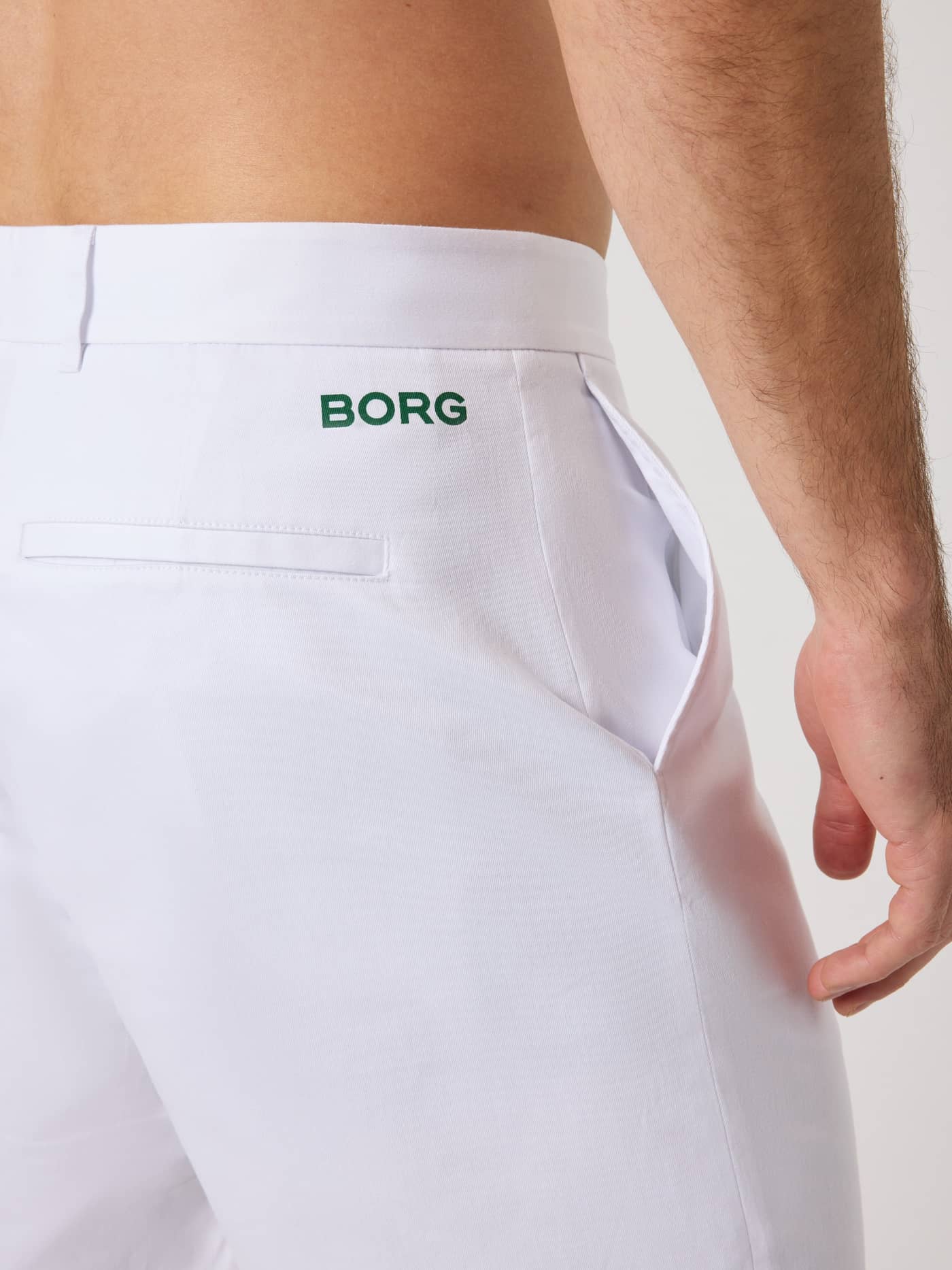 Detailed close-up of the green logo on the Brilliant White (White) Borg Golf Chinos Shorts for men with functional pockets. - Image 4