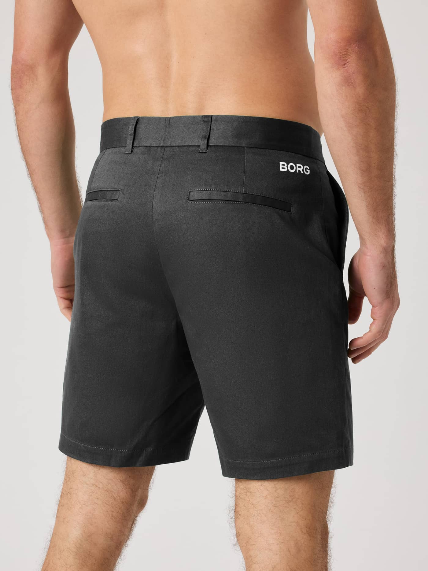 Back view of a man wearing the Borg Golf Chinos Shorts in Black Beauty (Black) with a white logo for golf and tennis style. - Image 2