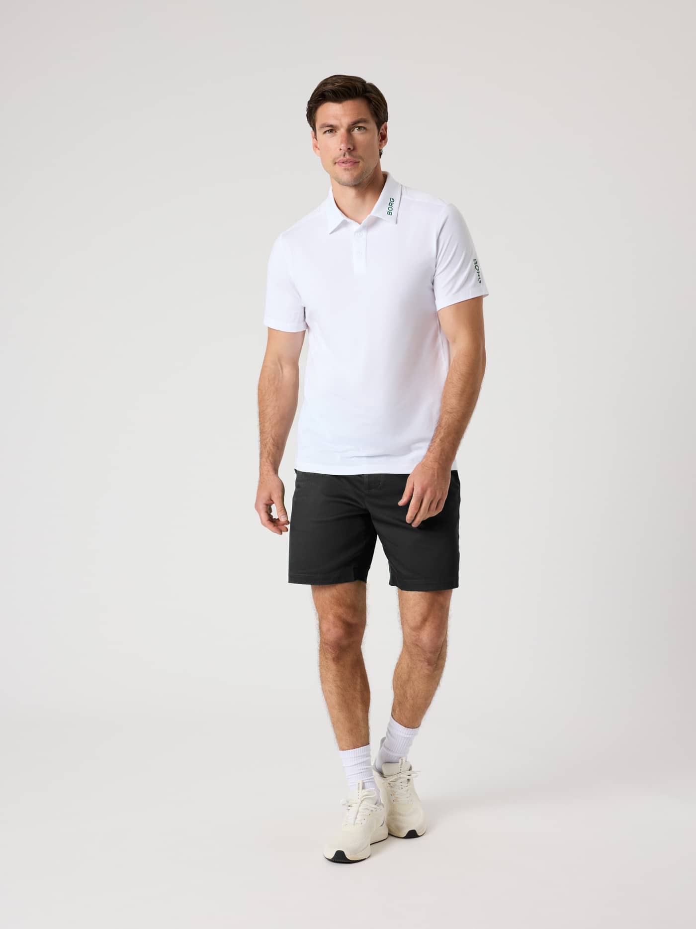 Full-body front view of a man wearing stylish, functional Borg Golf Chinos Shorts in Black Beauty (Black) with a white logo. - Image 3