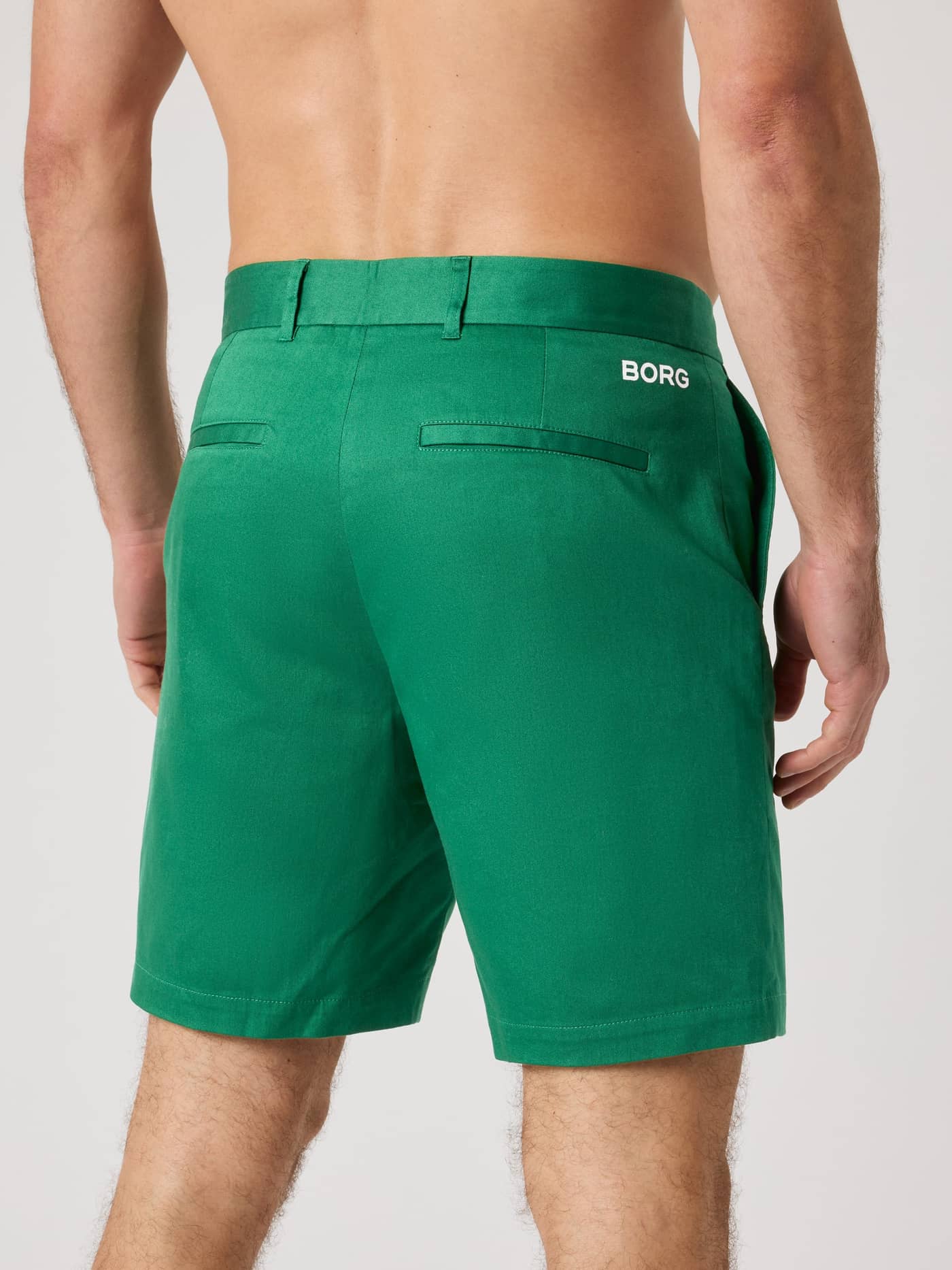 Back view of a man wearing stretchy Borg Golf Chinos Shorts in Verdant Green (Green) with a signature white logo. - Image 2