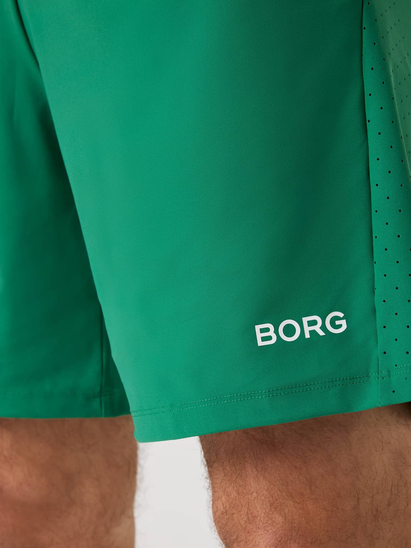 Close-up of the white logo on the men's Verdant Green (Green) Borg Golf Sports Shorts 8 Inch with perforated sides. - Image 4