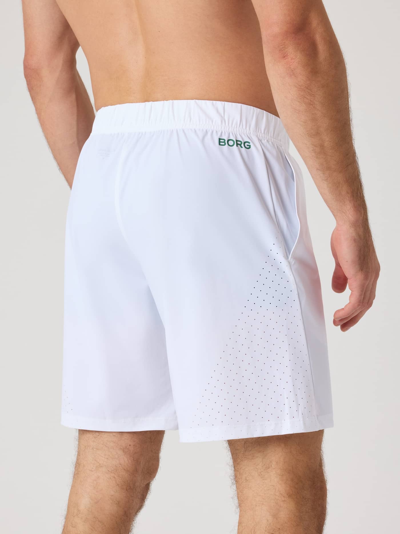 Back view of a man wearing the Borg Golf Sports Shorts 8 Inch in Brilliant White (White) with a green logo and side detail. - Image 2