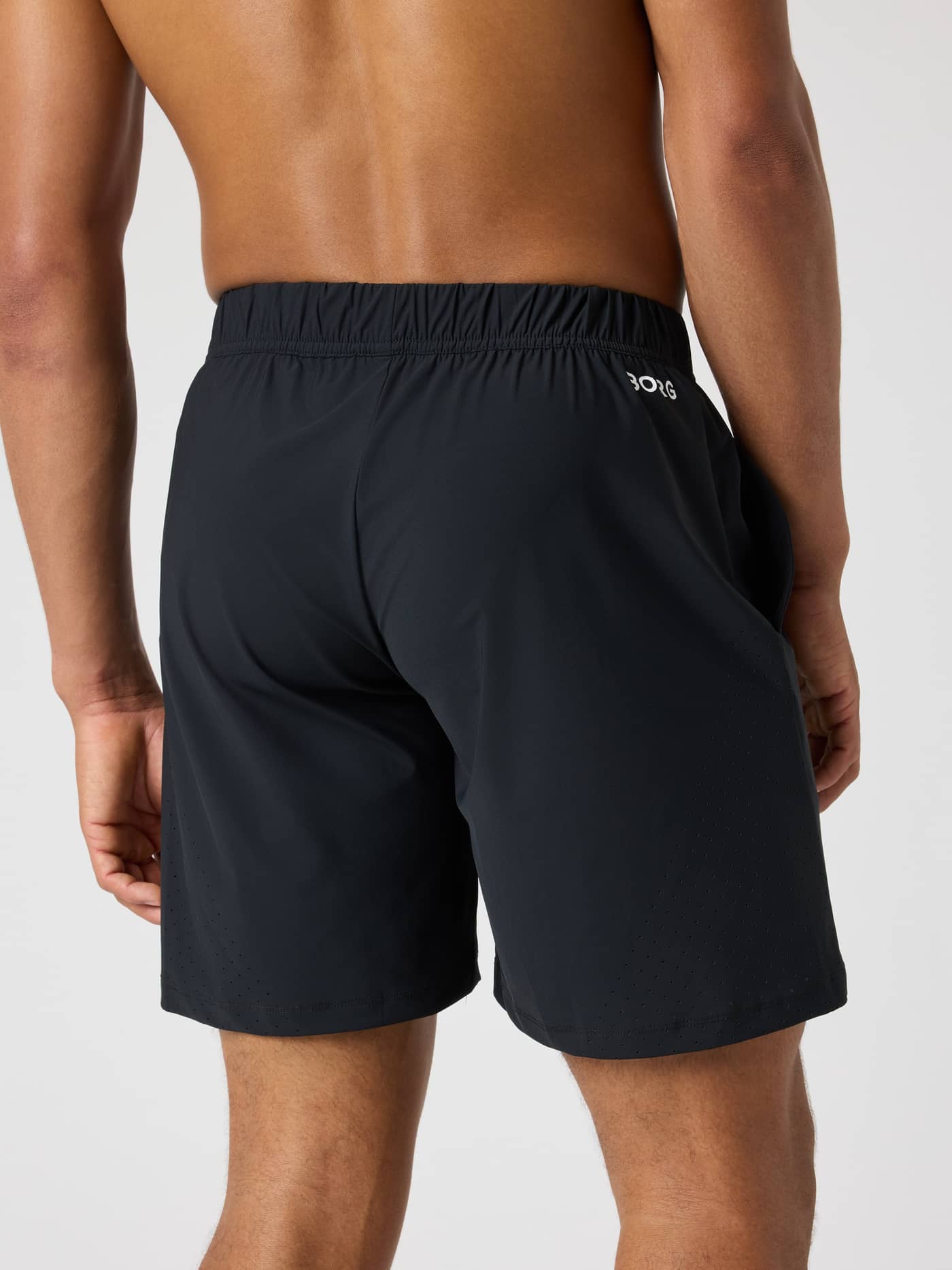 Back view of a man wearing the Borg Golf Sports Shorts 8 Inch in Black Beauty (Black) with a white logo. - Image 2